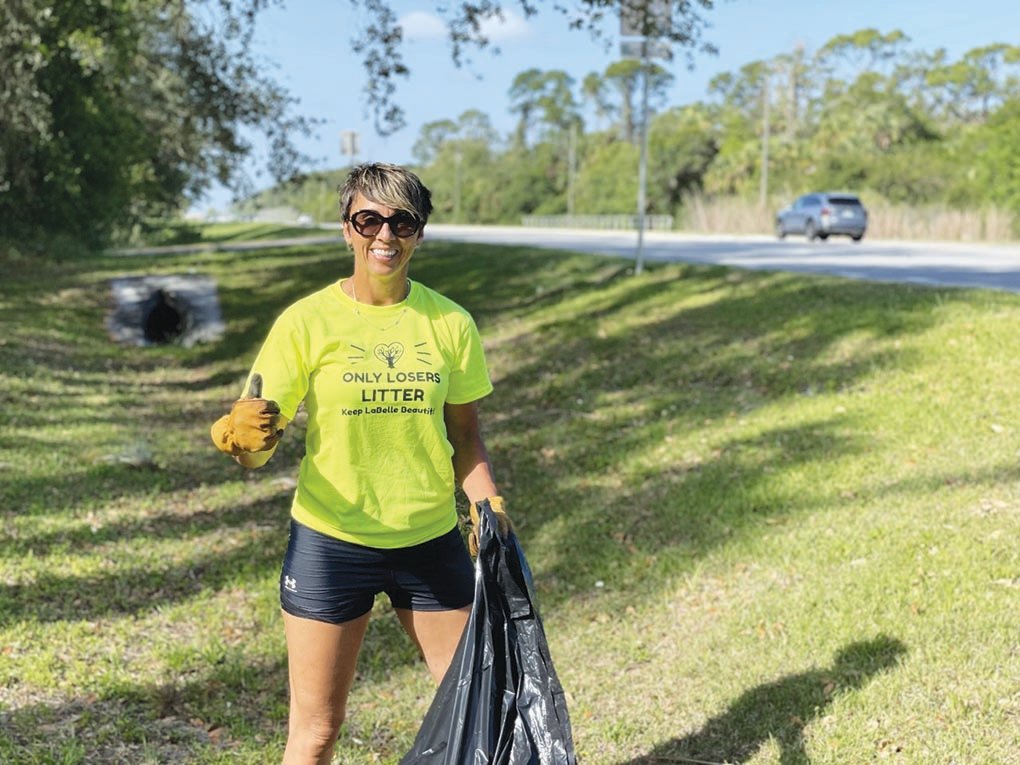 A volunteer at last year's Keep LaBelle Beautiful event collects debris along a roadway.